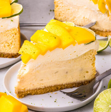 a slice of mango key lime cheesecake topped with fresh mango slices