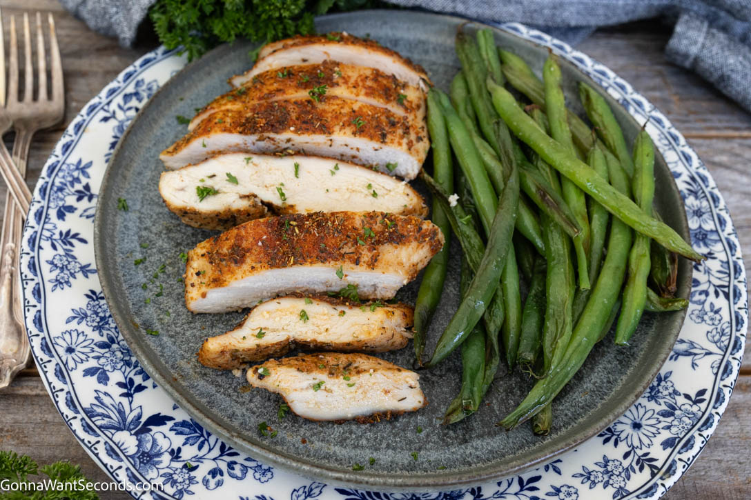 sliced baked boneless chicken breast with vegetables on the side