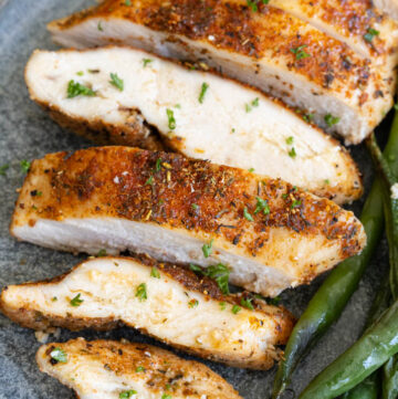 sliced baked boneless chicken breast with vegetables on the side