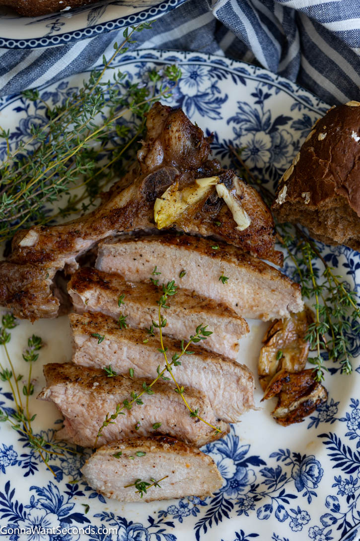 These pan seared pork chops are juicy, tender, and finished with a golden skillet crust, garlic butter, and fresh thyme. #porkchops #pansearedporkchops sliced pan seared pork chops on a plate