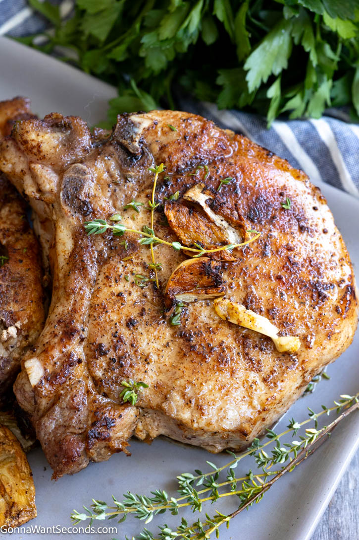 These pan seared pork chops are juicy, tender, and finished with a golden skillet crust, garlic butter, and fresh thyme. #porkchops #pansearedporkchops pan seared pork chops on a plate