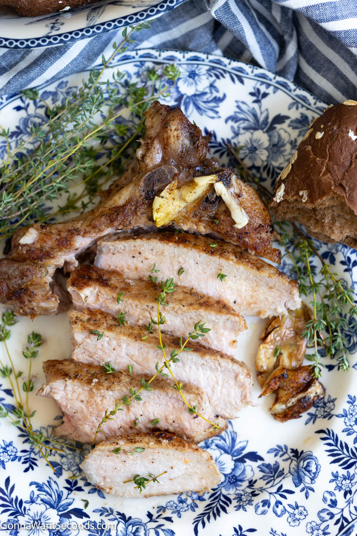 These pan seared pork chops are juicy, tender, and finished with a golden skillet crust, garlic butter, and fresh thyme. #porkchops #pansearedporkchops sliced pan seared pork chops on a plate