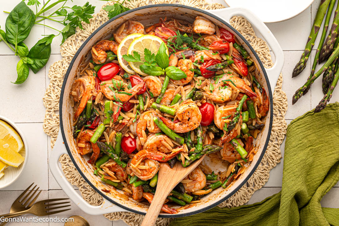 This shrimp orzo recipe is an easy one-pan dinner with juicy shrimp, tender orzo, asparagus, tomatoes, Parmesan, garlic, and fresh lemon. #shrimporzo #shrimprecipes shrimp orzo recipe in a skillet top shot