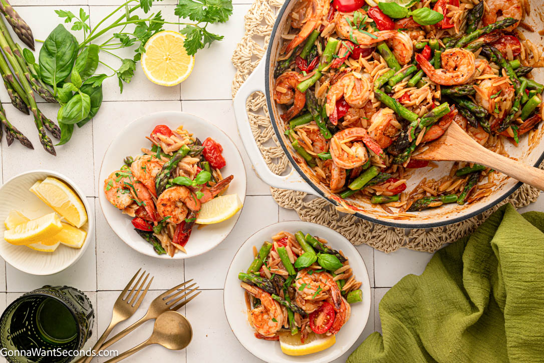 This shrimp orzo recipe is an easy one-pan dinner with juicy shrimp, tender orzo, asparagus, tomatoes, Parmesan, garlic, and fresh lemon. #shrimporzo #shrimprecipes shrimp orzo recipe in a skillet served on plates