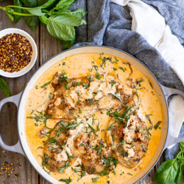 Marry Me Chicken in a pan full of its sauce topped with chopped basil