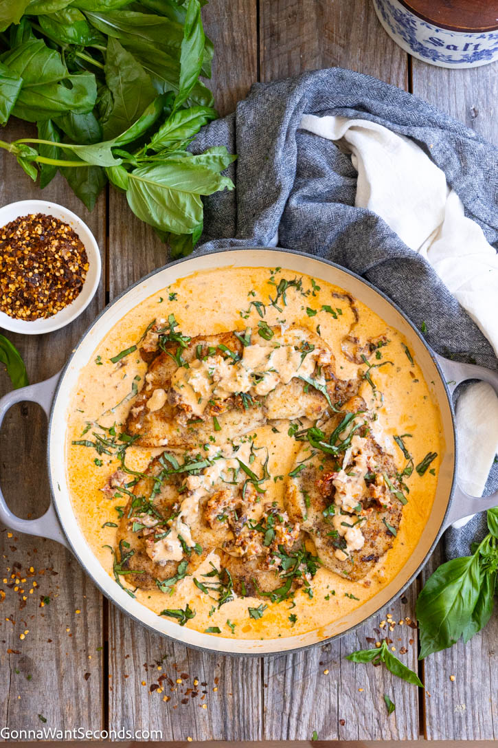 This Marry Me Chicken recipe features juicy chicken breasts in a rich, creamy Parmesan sun-dried tomato sauce. An easy restaurant-quality dinner ready in about 45 minutes. #marrymechicken #easychickenrecipe Marry Me Chicken in a pan full of its sauce topped with chopped basil