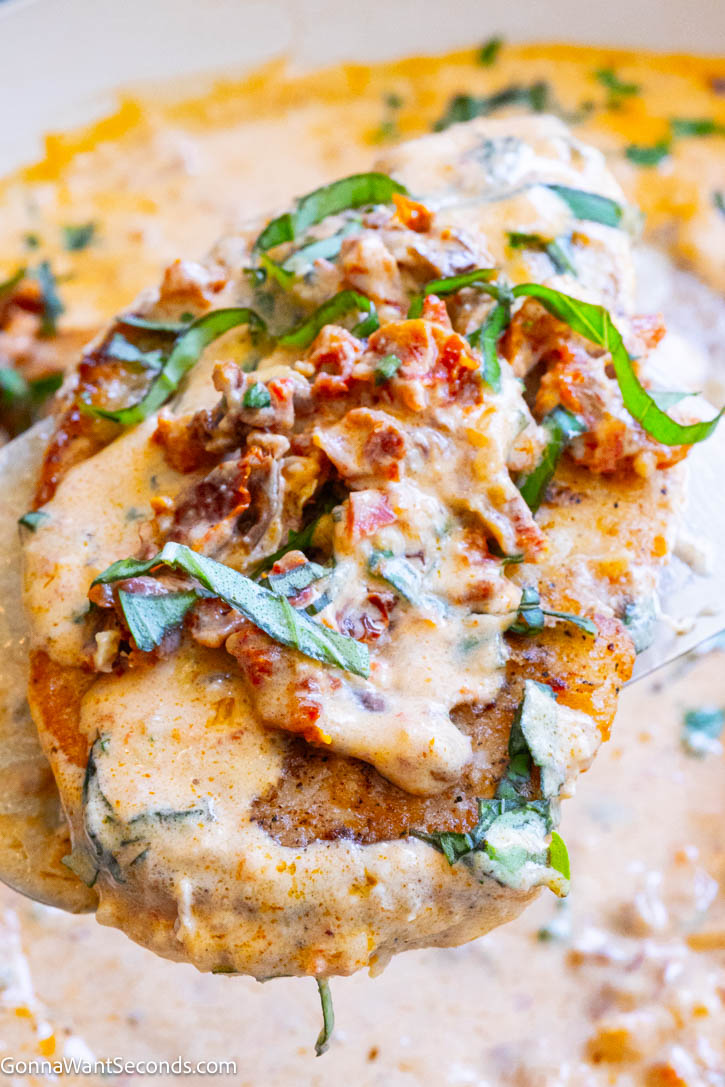 This Marry Me Chicken recipe features juicy chicken breasts in a rich, creamy Parmesan sun-dried tomato sauce. An easy restaurant-quality dinner ready in about 45 minutes. #marrymechicken #easychickenrecipe A piece of Marry Me Chicken smothered in its sauce topped with chopped basil and sun dried tomatoes