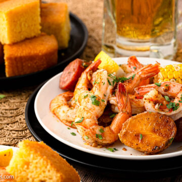 sheet pan shrimp boil on plate with cornbread on the side