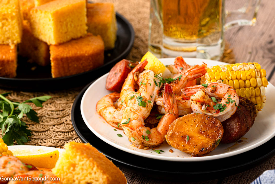 sheet pan shrimp boil on plate with cornbread on the side