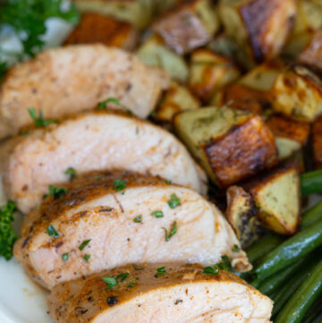 slices of Baked Pork Tenderloin with roasted veggies on the side, on a plate