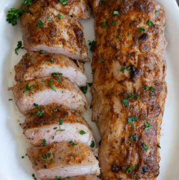 Sliced and whole baked pork tenderloin, both on a serving platter