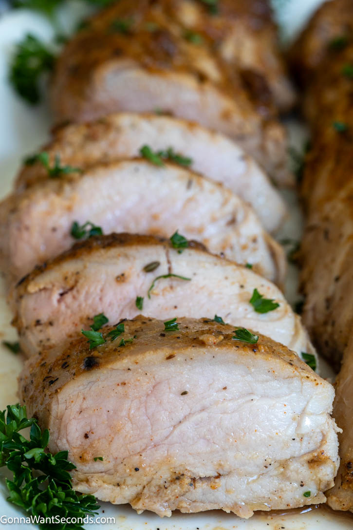 This Baked Pork Tenderloin is juicy, tender, and packed with flavor. An easy oven recipe with no searing or marinating required! #bakedporktenderloin #porktenderloin slices of Baked Pork Tenderloin close up