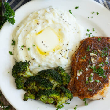 Baked Pork Chops on a plate with mashed potatoes and roasted broccoli on the side