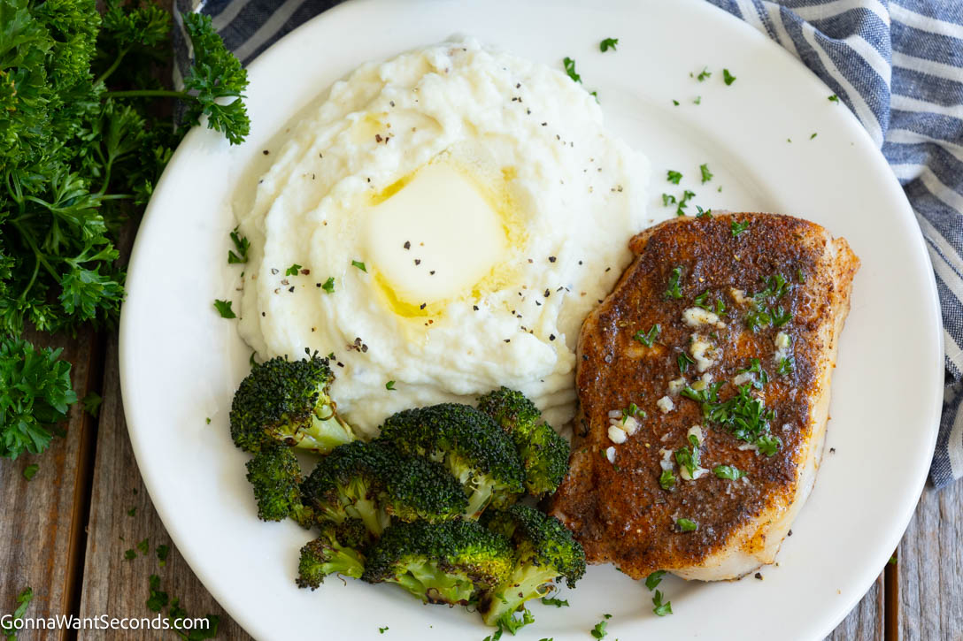 These juicy Baked Pork Chops are seasoned with pantry spices, baked to perfection, and finished with rich garlic butter. An easy 30-minute dinner the whole family will love. #bakedporkchops #porkchops Baked Pork Chops on a plate with mashed potatoes and roasted broccoli on the side