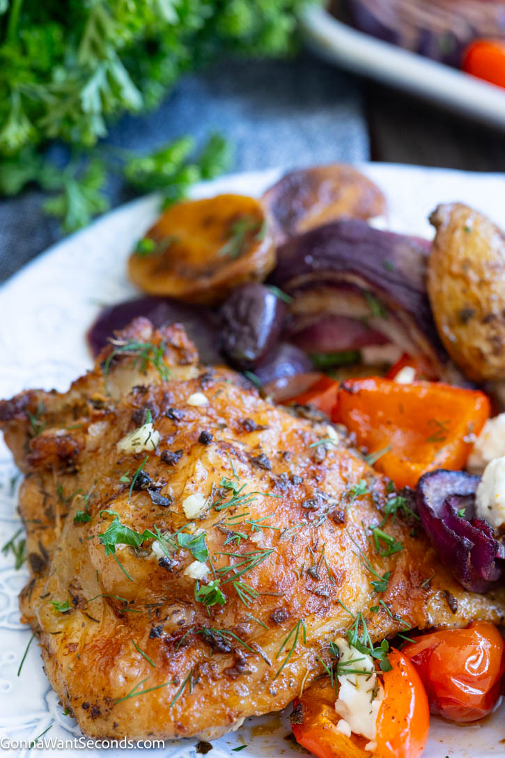 Greek sheet pan chicken with juicy thighs, tender potatoes, colorful vegetables, feta, and a bright lemon-herb sauce. An easy one-pan dinner. #greekchicken #sheetpanchicken Greek sheet pan chicken with juicy thighs, tender potatoes, colorful vegetables, on a plate