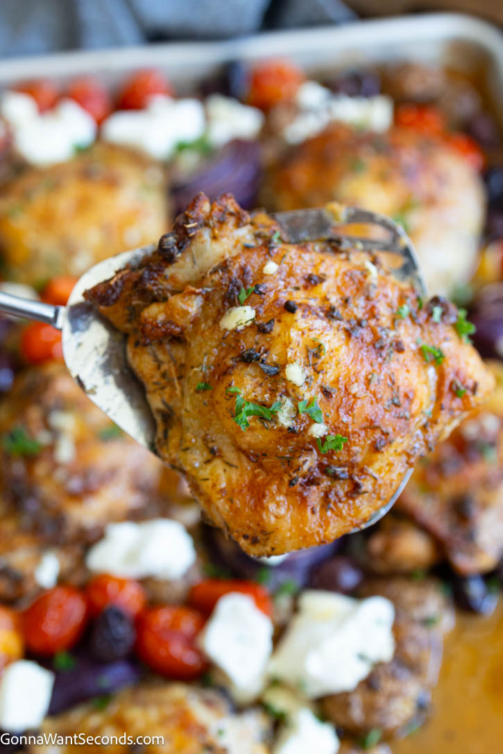 Greek sheet pan chicken with juicy thighs, tender potatoes, colorful vegetables, feta, and a bright lemon-herb sauce. An easy one-pan dinner. #greekchicken #sheetpanchicken reek sheet pan chicken with juicy close up