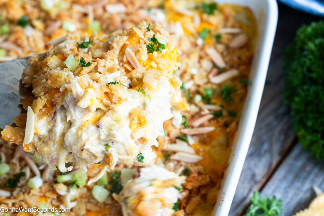 Neiman Marcus Chicken Casserole is creamy, cheesy, and loaded with tender chicken, bacon, and a buttery Ritz cracker topping. #chickencasserole #neimanmarcus Scooping a portion of Neiman Marcus Chicken Casserole