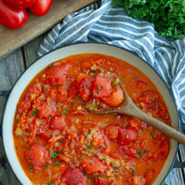 stewed tomatoes in a pan with a wooden spoon