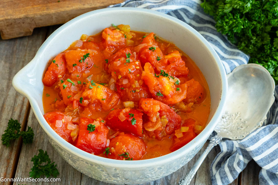 Learn how to make old-fashioned Stewed Tomatoes with fresh Roma tomatoes, onion, celery, butter, and a touch of sugar for a classic comfort-food side. #stewedtomatoes #sidedishes stewed tomatoes in a bowl