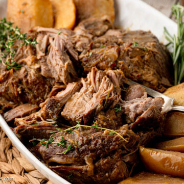 Apple cider braised pork shoulder with apples on a serving platter