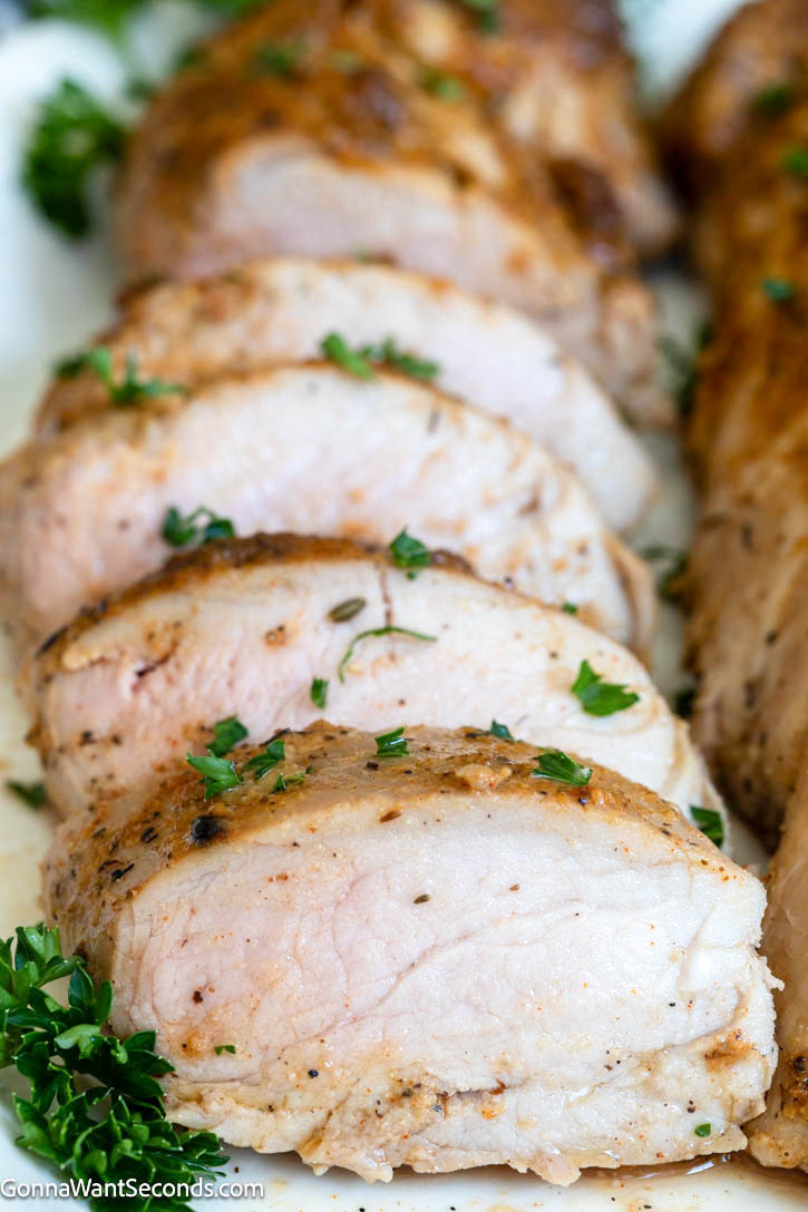This Baked Pork Tenderloin is juicy, tender, and packed with flavor. An easy oven recipe with no searing or marinating required! #bakedporktenderloin #porktenderloin slices of Baked Pork Tenderloin close up
