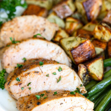 slices of Baked Pork Tenderloin with roasted veggies on the side, on a plate