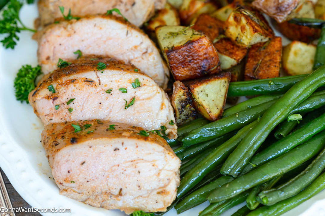 slices of Baked Pork Tenderloin with roasted veggies on the side, on a plate