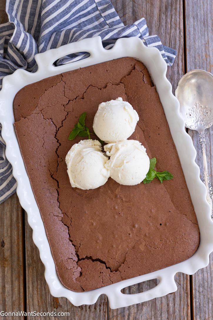 Crack through the delicate crust of Ina Garten Brownie Pudding into a rich, fudgy center. Serve warm with melting vanilla ice cream for pure chocolate bliss! #browniepudding #inagartenrecipe Freshly baked Ina Garten brownie pudding in a white scalloped casserole dish, topped with three scoops of vanilla ice cream and fresh mint leaves.